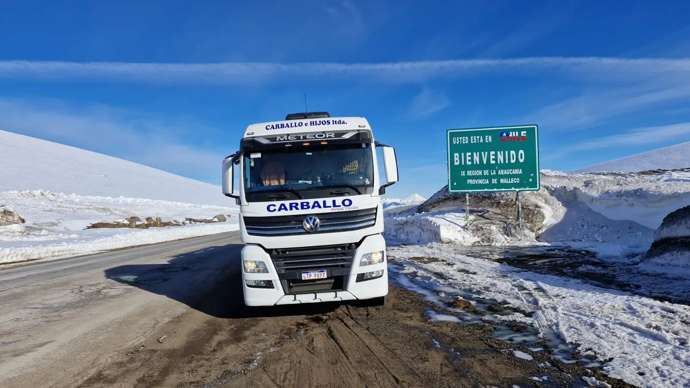 Camión de Carballo e Hijos junto al cartel de bienvenida en un paso de frontera nevado